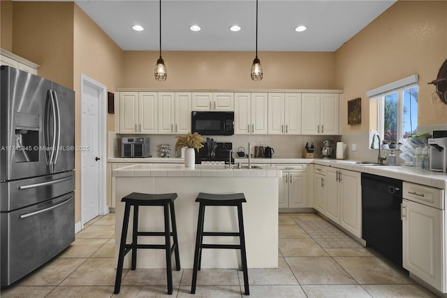 kitchen with sink, black appliances, hanging light fixtures, a center island with sink, and white cabinets