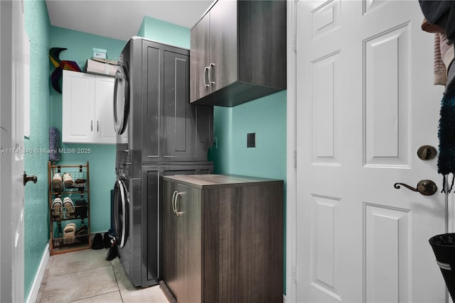 washroom featuring cabinets, stacked washing maching and dryer, and light tile patterned floors