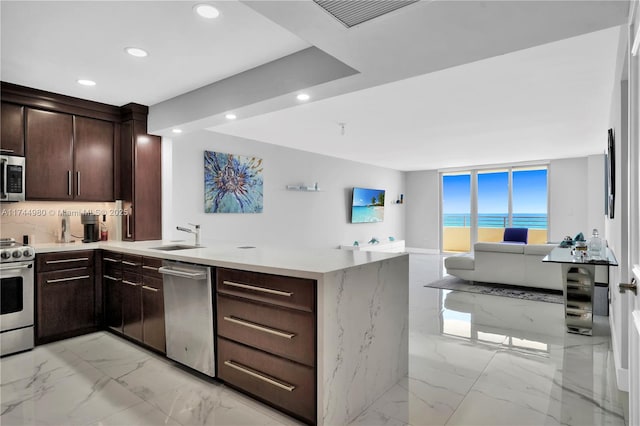 kitchen featuring dark brown cabinetry, sink, stainless steel appliances, and kitchen peninsula