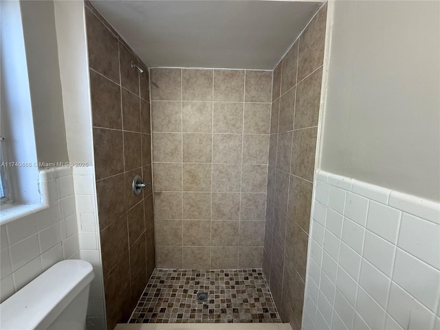 bathroom featuring tile walls, toilet, and tiled shower