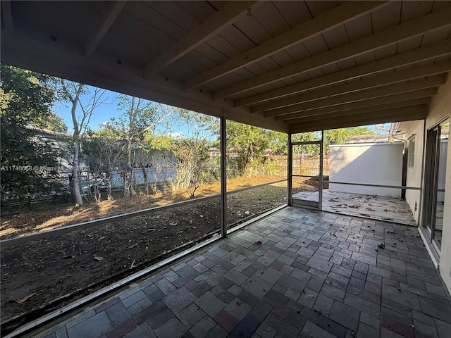 unfurnished sunroom featuring beam ceiling