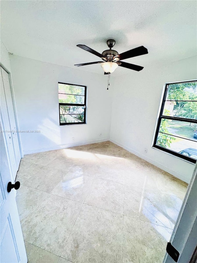 unfurnished room with ceiling fan and a textured ceiling