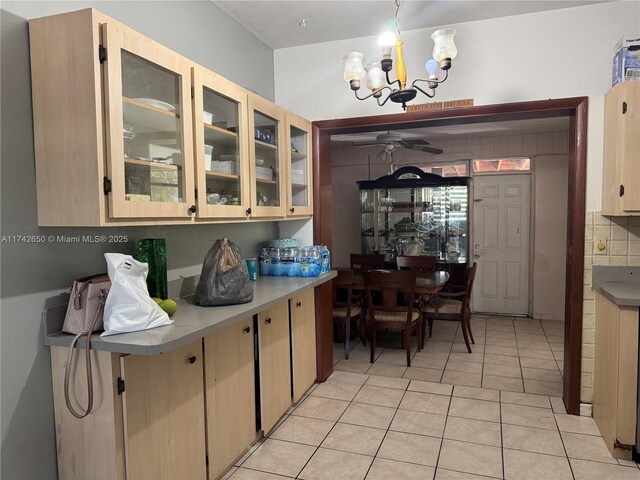 1445 NE 136th St, North Miami, FL 33161 - kitchen featuring a chandelier, light tile patterned floors, ceiling fan, glass insert cabinets, and backsplash