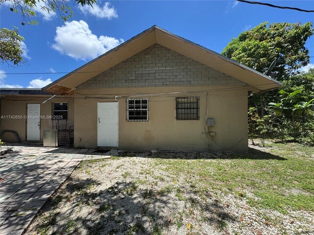 1445 NE 136th St, North Miami, FL 33161 - view of property exterior featuring a patio area, stucco siding, and a lawn