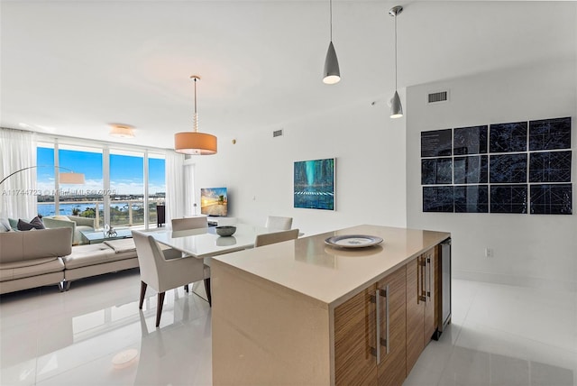 kitchen featuring a kitchen island, light tile patterned flooring, a water view, and expansive windows