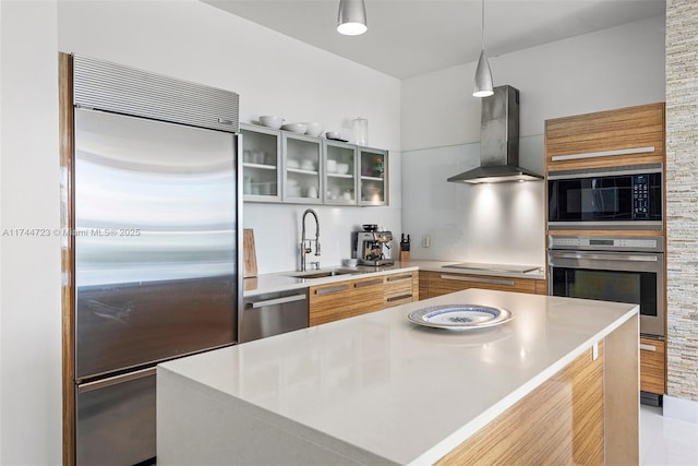 kitchen featuring sink, black appliances, a kitchen island, pendant lighting, and wall chimney range hood