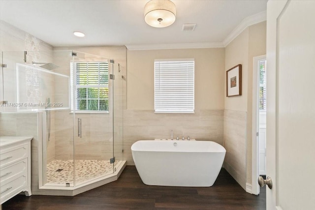 bathroom with tile walls, hardwood / wood-style floors, vanity, ornamental molding, and plus walk in shower