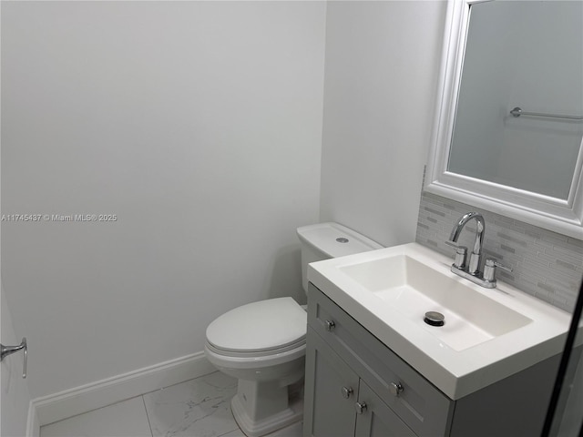 bathroom with toilet, vanity, marble finish floor, baseboards, and decorative backsplash