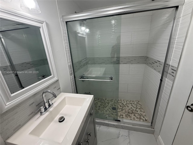 bathroom featuring marble finish floor, vanity, decorative backsplash, and a shower stall