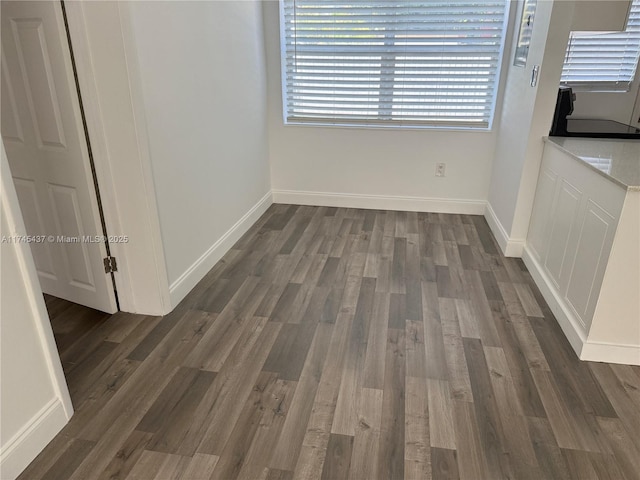unfurnished dining area with dark wood-type flooring and baseboards
