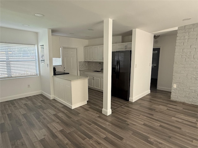 kitchen with light countertops, a sink, white cabinetry, black refrigerator with ice dispenser, and dark wood-style flooring