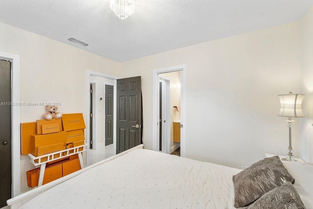 bedroom featuring ensuite bath and a textured ceiling