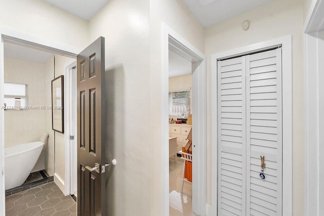 hallway with tile walls and dark tile patterned flooring