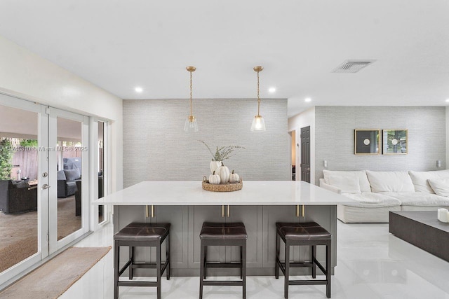 kitchen featuring pendant lighting, a spacious island, a kitchen bar, and french doors