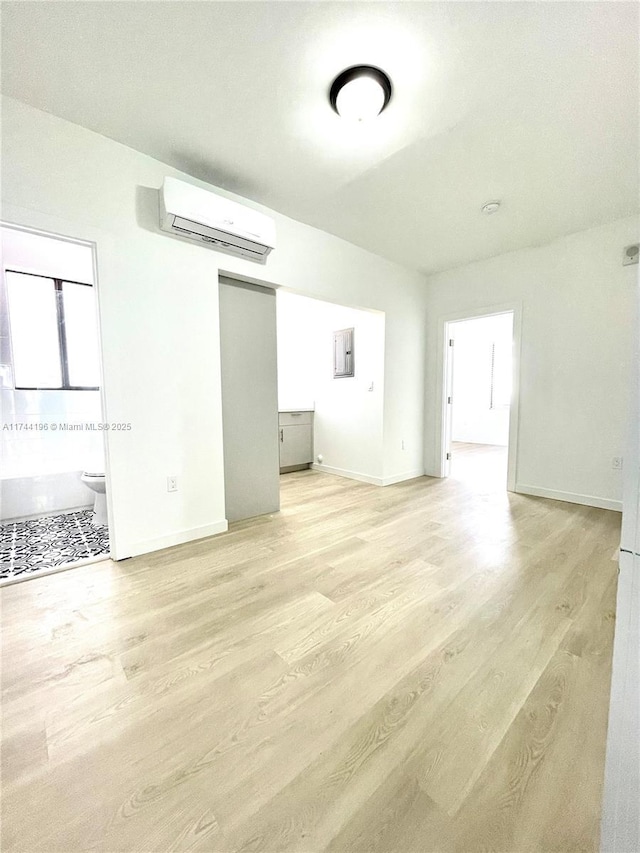 spare room with a wall unit AC and light hardwood / wood-style floors