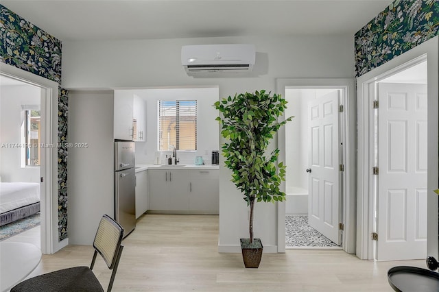 kitchen featuring sink, plenty of natural light, an AC wall unit, and stainless steel refrigerator