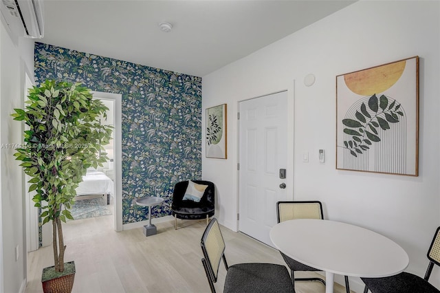 dining space featuring a wall mounted AC and light hardwood / wood-style floors