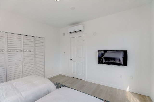 bedroom with light hardwood / wood-style flooring, a closet, and a wall mounted AC