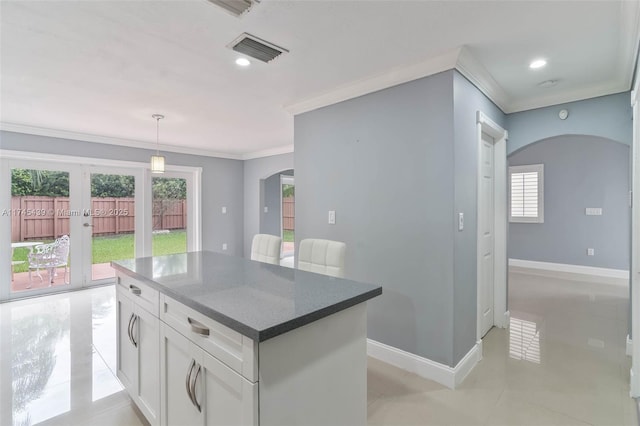 kitchen featuring a center island, white cabinetry, pendant lighting, dark stone counters, and crown molding