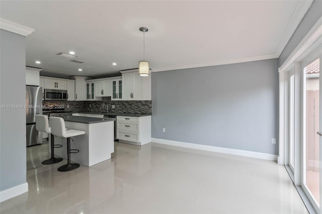 kitchen with stainless steel appliances, pendant lighting, white cabinets, and backsplash