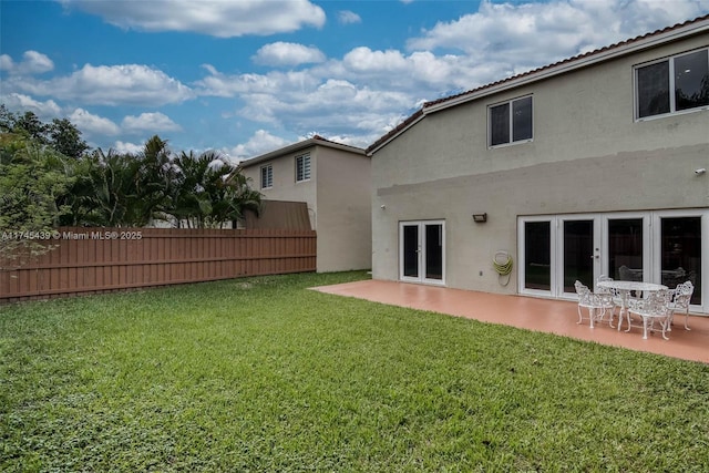 rear view of house with a patio area, french doors, and a lawn