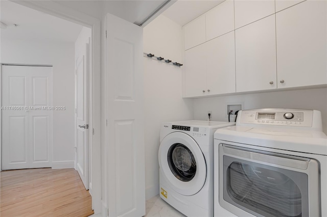 laundry area featuring washing machine and dryer and cabinets