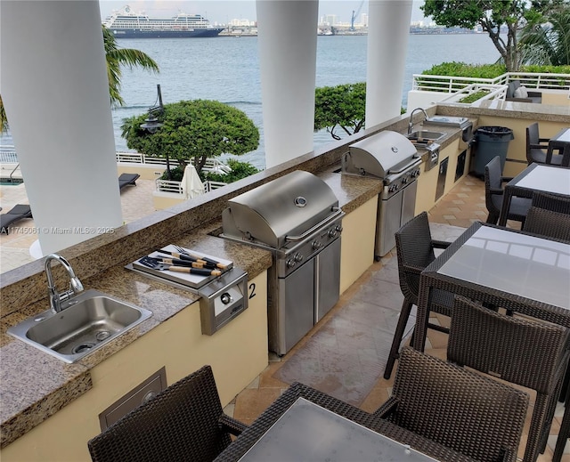 view of patio featuring sink, grilling area, a water view, and an outdoor kitchen