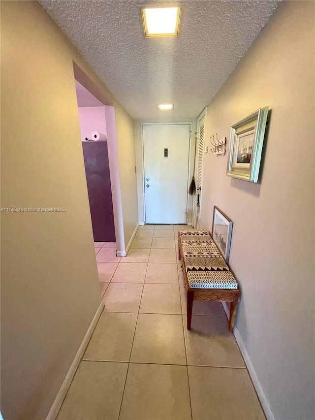 hall with light tile patterned floors and a textured ceiling