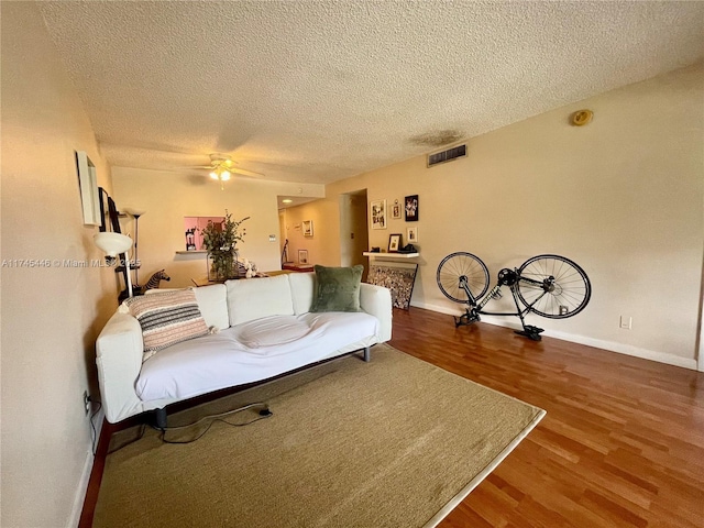 living room with hardwood / wood-style floors, a textured ceiling, and ceiling fan