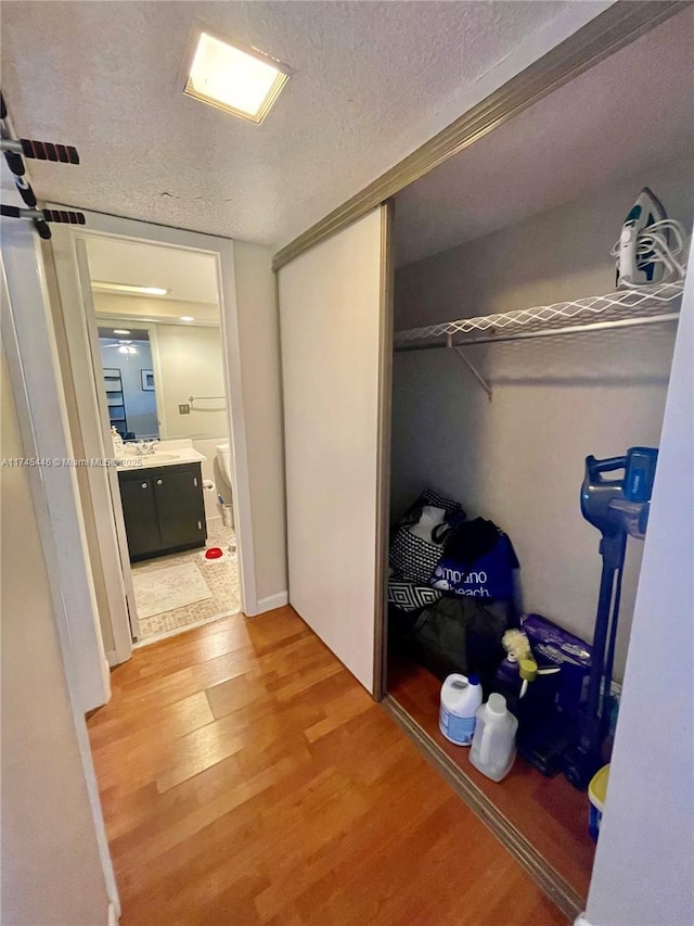 hallway featuring light hardwood / wood-style flooring and a textured ceiling