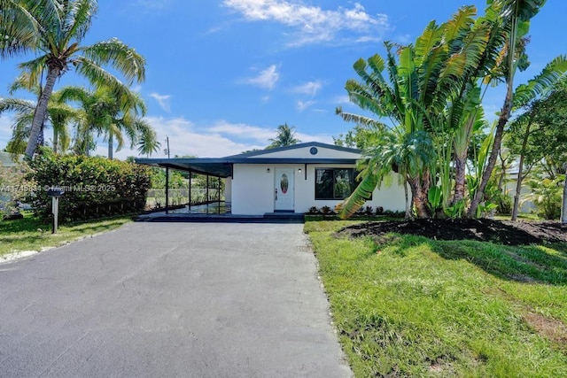 view of front of property featuring a carport, aphalt driveway, a front lawn, and stucco siding