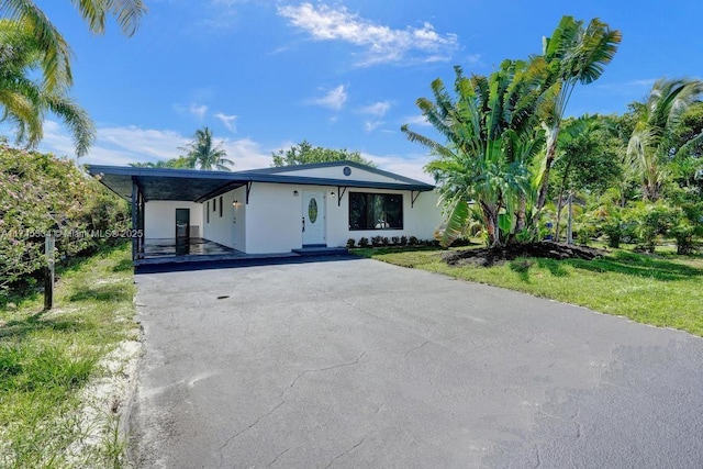 view of front of house featuring a front lawn, aphalt driveway, and stucco siding