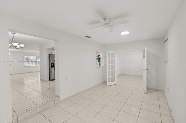 unfurnished room featuring ceiling fan with notable chandelier, light tile patterned floors, and french doors