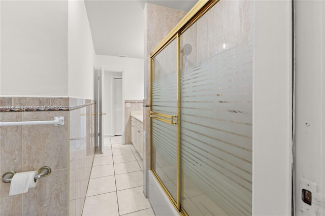 bathroom with vanity, shower / bath combination with glass door, tile patterned flooring, and tile walls