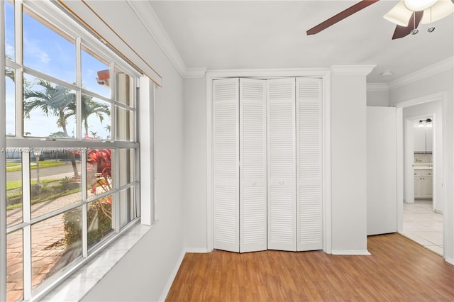 unfurnished bedroom with crown molding, light hardwood / wood-style flooring, a closet, and ceiling fan