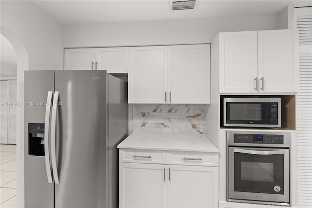 kitchen featuring white cabinetry, appliances with stainless steel finishes, light tile patterned floors, and decorative backsplash