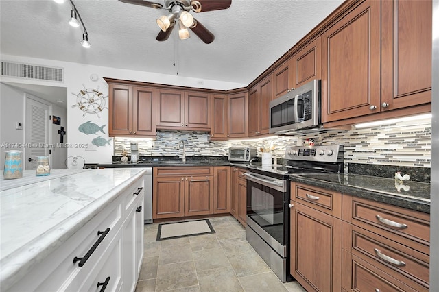 kitchen with sink, stainless steel appliances, light stone counters, white cabinets, and decorative backsplash