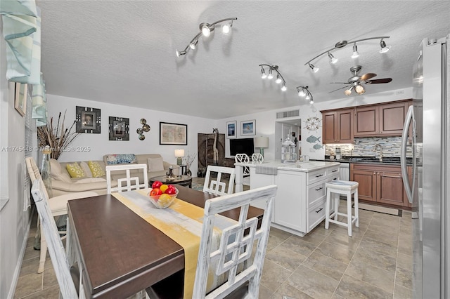 dining room with ceiling fan, sink, and a textured ceiling