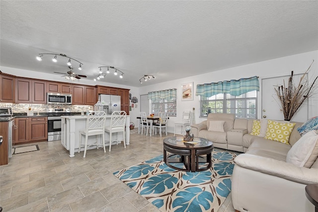 living room featuring ceiling fan and a textured ceiling