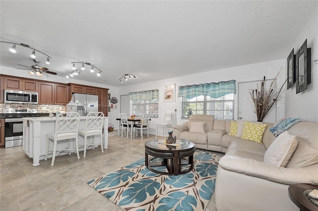 living room featuring ceiling fan and a textured ceiling