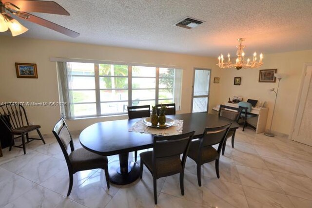 dining area with ceiling fan with notable chandelier and a textured ceiling