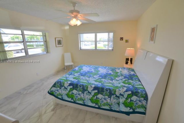 bedroom with ceiling fan and a textured ceiling