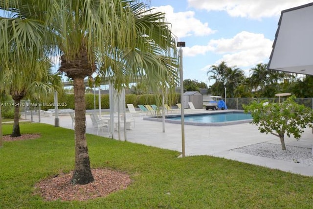 view of swimming pool with a yard, a storage unit, and a patio