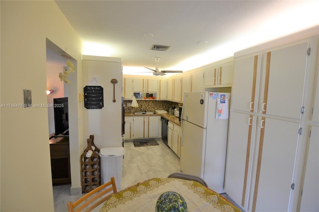 kitchen with dishwasher, white fridge, backsplash, and cream cabinetry