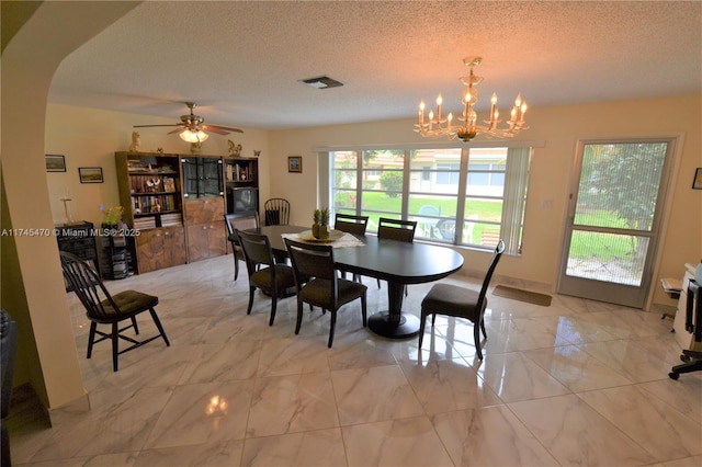 dining room featuring ceiling fan with notable chandelier and a textured ceiling