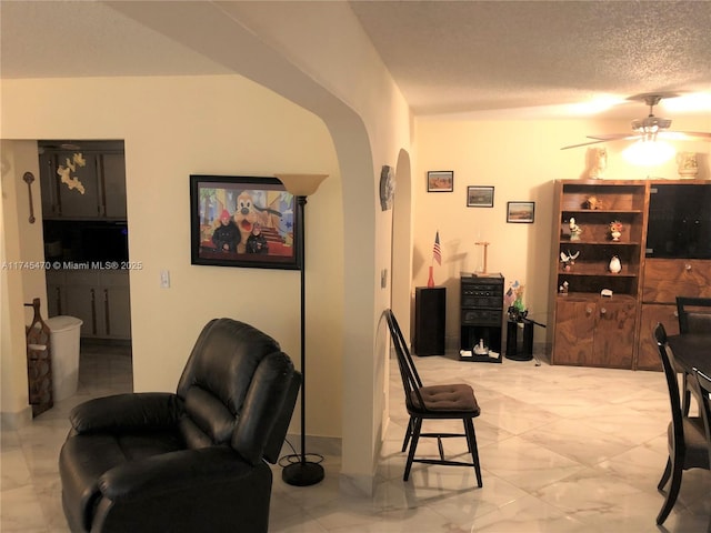 living room featuring ceiling fan and a textured ceiling