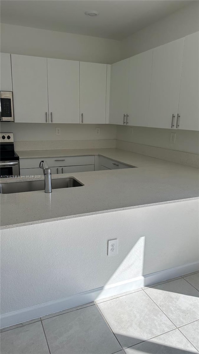 kitchen with white cabinetry, sink, light tile patterned floors, and stainless steel appliances