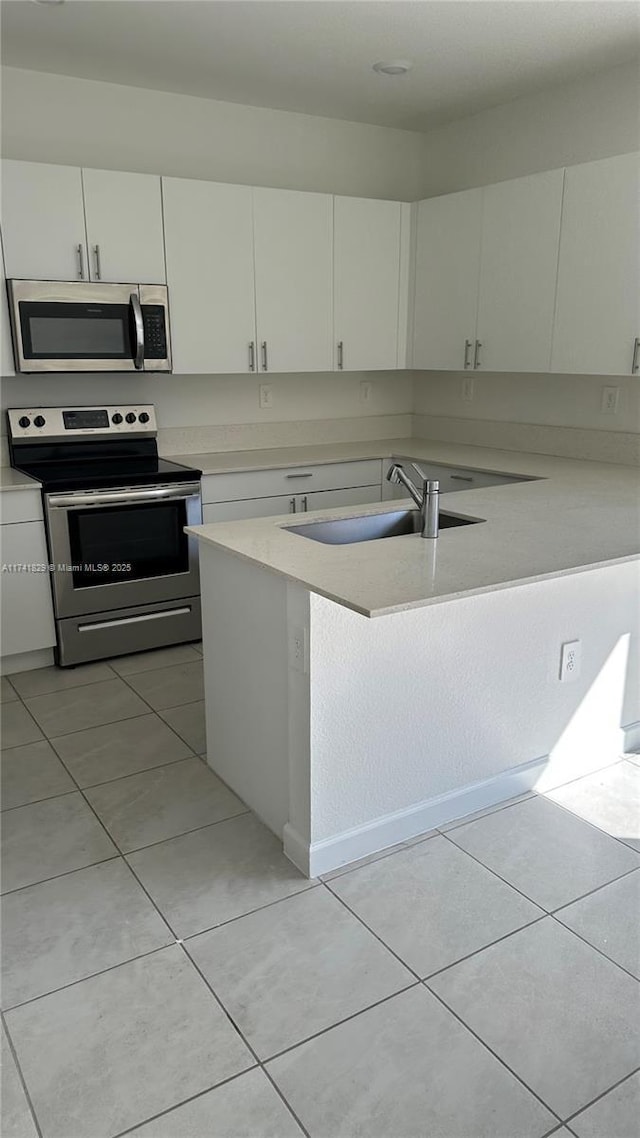 kitchen featuring light tile patterned flooring, stainless steel appliances, sink, and white cabinets