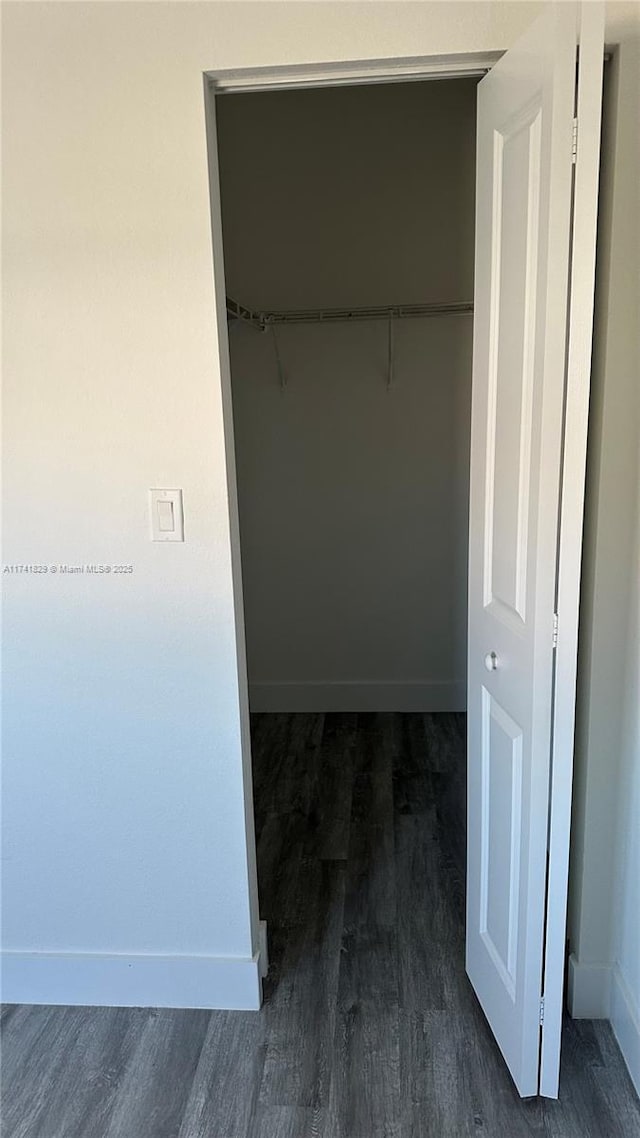 walk in closet with dark wood-type flooring