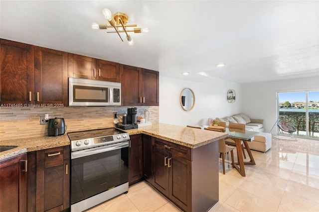 kitchen with stainless steel appliances, light stone counters, tasteful backsplash, light tile patterned flooring, and kitchen peninsula